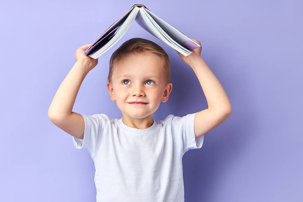 Smiling boy with book above head - Foto, Bild