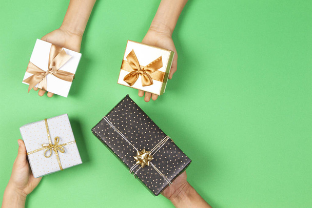 Handen vasthouden presenteert verpakt in cadeaupapier op lichtgroene achtergrond. Kerstmis, Nieuwjaar, vakantie concept - Foto, afbeelding