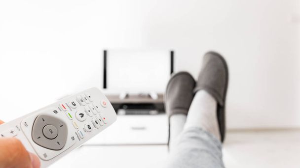 Mann sieht Fernseher mit Beinen auf dem Wohnzimmertisch. - Foto, Bild