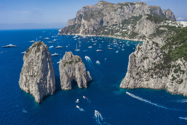 Vista aérea de los peñascos de piedra caliza faraglioni en verano en el mar Tirreno con yates frente a la isla de Capri
 - Foto, imagen