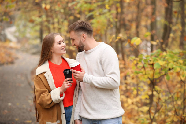 Amar pareja joven con tazas de café caliente en el parque de otoño
 - Foto, imagen