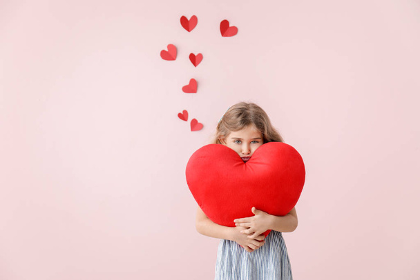 Милая маленькая девочка с подушкой в форме сердца на цветном фоне. Празднование Дня Святого Валентина
 - Фото, изображение
