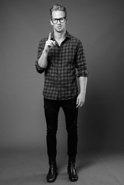 Studio shot of young handsome hipster man in black and white - Foto, Imagen