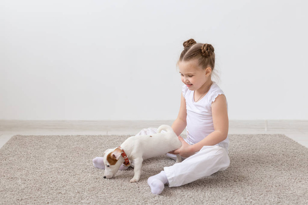 Pet, bambini e concetto animale - Bambina che tiene un cucciolo per le zampe
 - Foto, immagini