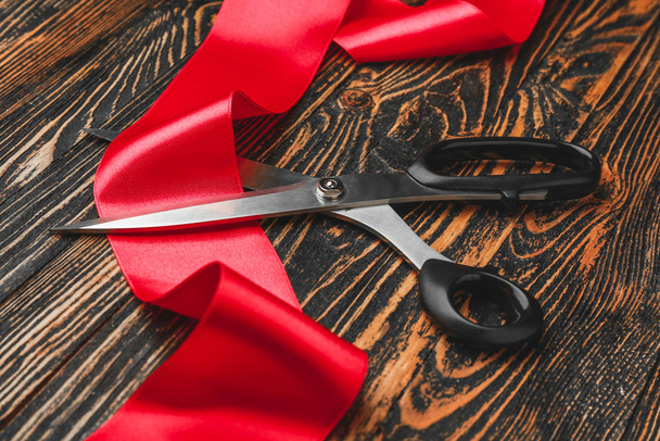 Ножницы и красная лента на деревянном фоне
 - Фото, изображение