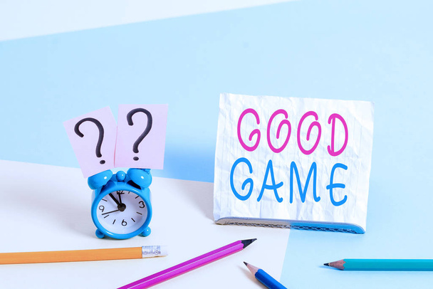 Writing note showing Good Game. Business photo showcasing term frequently used in multiplayer gaming at the end of a match Mini size alarm clock beside stationary on pastel backdrop. - Foto, imagen