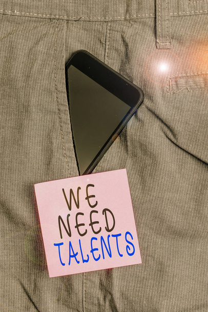 Texte manuscrit We Need Talents. Concept signifiant la recherche de recruteurs créatifs pour rejoindre l'entreprise ou l'équipe Smartphone dispositif à l'intérieur pantalon de travail formel poche avant près du papier de note
. - Photo, image