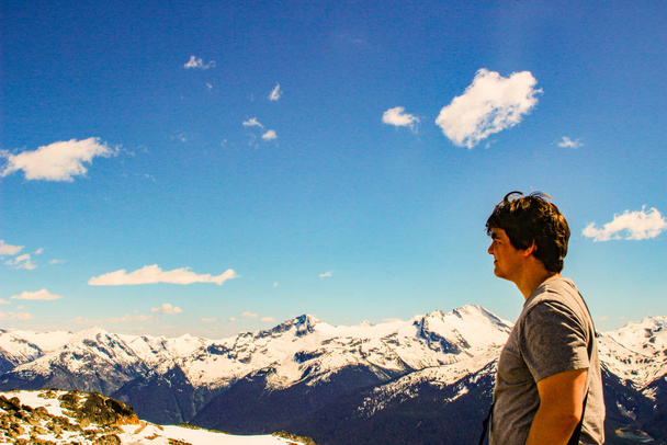 турист с рюкзаком стоит на вершине горы, свистит Британская Колумбия. Тема туризма
. - Фото, изображение