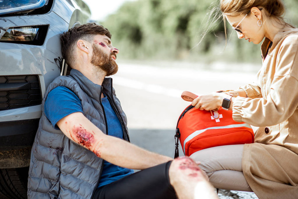 Женщина-водитель с раненым мужчиной на дороге
 - Фото, изображение