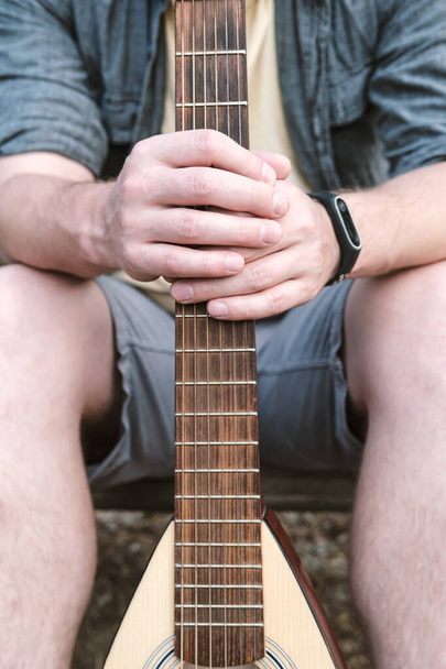 Mens hands hold an acoustic guitar for traveling behind a griff or neck. - Foto, imagen