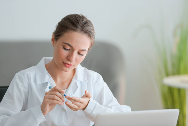 Femme diabétique vérifiant le taux de sucre dans le sang au bureau
 - Photo, image