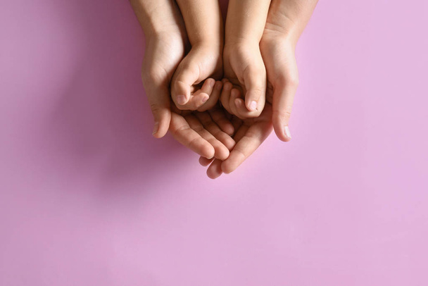 Mother holding hands with her child on pink background, top view. Happy family - Valokuva, kuva