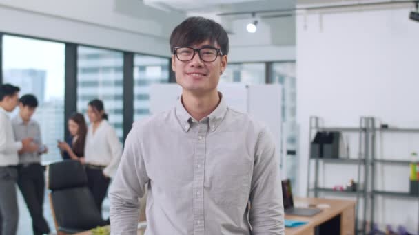 Portrait of successful handsome executive businessman smart casual wear looking at camera and smiling, arms crossed in modern office workplace. Young Asia guy standing in contemporary meeting room. - Footage, Video