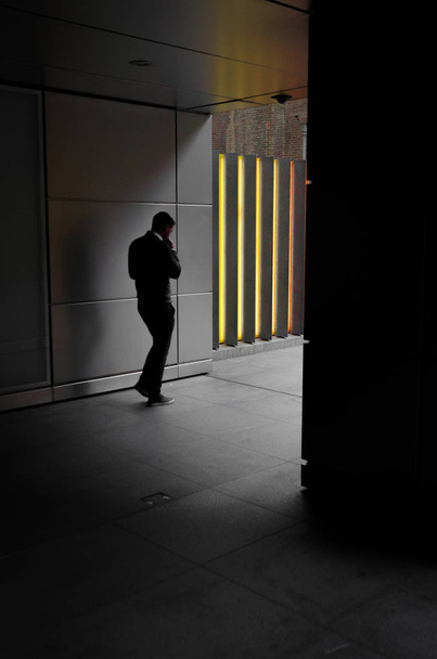 Een zakenman loopt naar een kleurrijke muur terwijl hij nadenkt over zijn gedachten - Foto, afbeelding