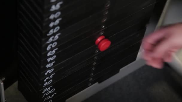 Az erős sportoló súlyt helyez egy blokk szimulátorra.. - Felvétel, videó