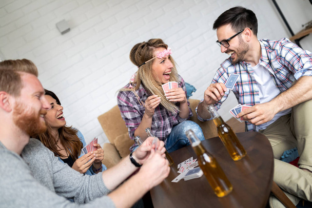 Happy group of friends playing cards and drinking - Foto, imagen