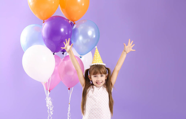 Menina feliz com balões de ar de aniversário no fundo de cor
 - Foto, Imagem