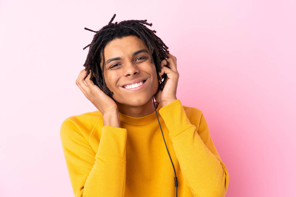 Young African American man listening music over isolated pink wa - Photo, Image