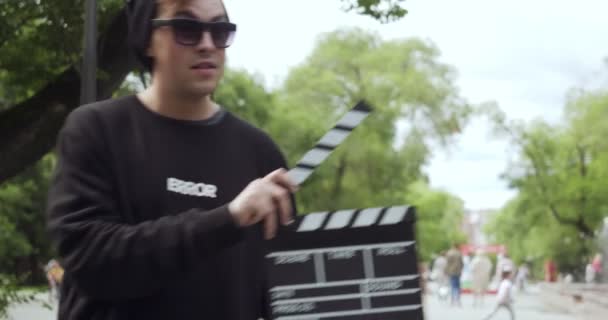 Young man with clapperboard appears and leaves the frame. - Footage, Video