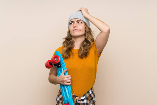 Young skater blonde girl over isolated background having doubts and with confuse face expression - Φωτογραφία, εικόνα