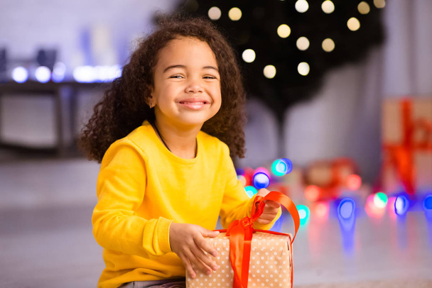 Alegre chica negra abriendo regalos en Nochebuena
 - Foto, Imagen