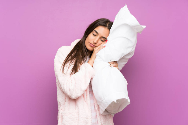 junge Frau im Schlafanzug und Morgenmantel vor isoliertem lila Hintergrund - Foto, Bild
