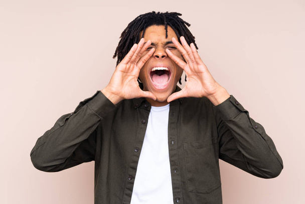 Mladý Afroameričan přes izolované pozadí křičí a něco ohlašuje - Fotografie, Obrázek