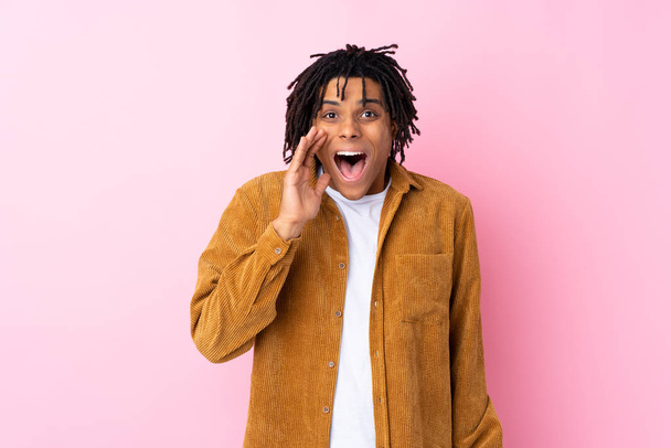 Giovane uomo afroamericano con giacca di velluto a coste su sfondo rosa isolato con sorpresa e espressione facciale scioccata
 - Foto, immagini