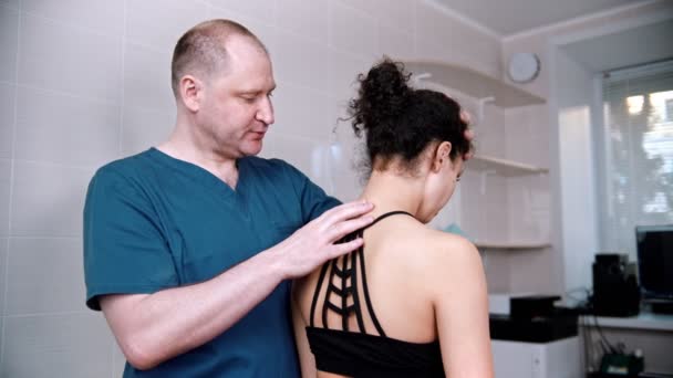 Chiropractic treatment - the doctor inspecting the young woman before the session - bending the neck up and down and to the sides - Кадры, видео