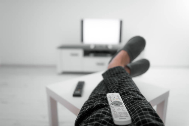 Man drinking soda juice and looking at TV with legs on the table - Photo, Image