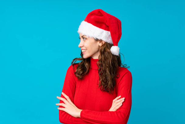Κορίτσι με χριστουγεννιάτικο καπέλο πάνω από απομονωμένο κίτρινο φόντο κοιτάζοντας στο πλάι - Φωτογραφία, εικόνα