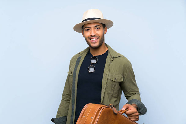 Молодой красивый мужчина держит винтажный портфель на изолированном синем фоне
 - Фото, изображение