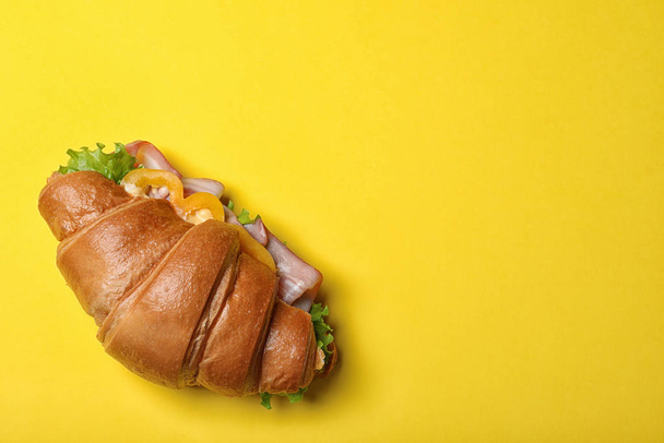 Tasty croissant sandwich with ham on yellow background, top view. Space for text - Foto, Bild
