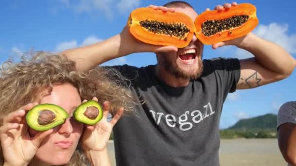 Amigos divertidos locos con ojos de fruta en la playa. Concepto de estilo de vida saludable
 - Imágenes, Vídeo