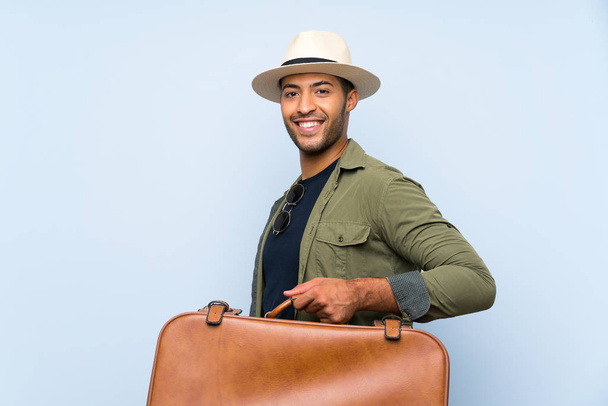 Young handsome man holding a vintage briefcase over isolated blue background smiling a lot - Foto, imagen