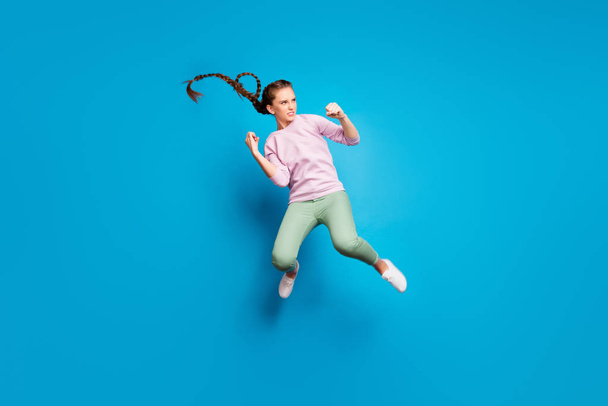 Full size profil stronie zdjęcie poważnej młodej dziewczyny mają walki skoku pięści kopnięcie wroga chcą wygrać nosić różowy pullover biały młodzież tenisówki izolowane na tle niebieskiego koloru - Zdjęcie, obraz