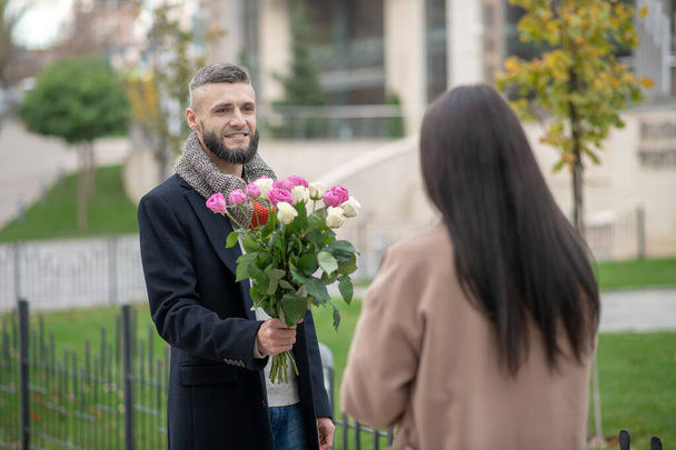 Vousatý mladý muž přichází na rande s květinami - Fotografie, Obrázek