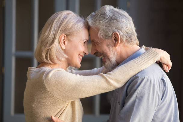 Elderly cheerful couple embracing looks at each other with love - Foto, afbeelding