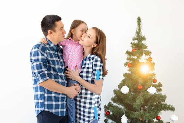 Ünnepek, ajándékok és karácsonyfa koncepció - Kis család, akik boldog időt töltenek együtt karácsonykor. - Fotó, kép