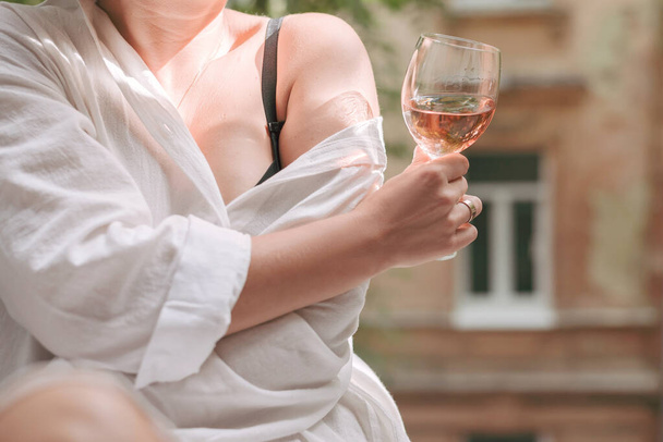 Sklenice růžového vína v ženské ruce proti pohledu na ulici. - Fotografie, Obrázek