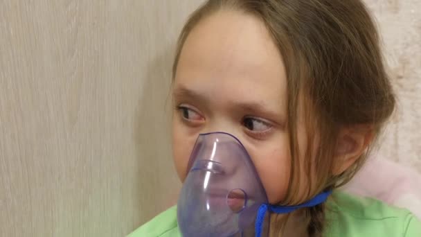 kind met tablet is ziek en ademt via een inhalator. close-up. klein meisje behandeld met een inhalatiemasker op haar gezicht in het ziekenhuis. Peuter behandelt griep door inhalatiedamp in te ademen. - Video