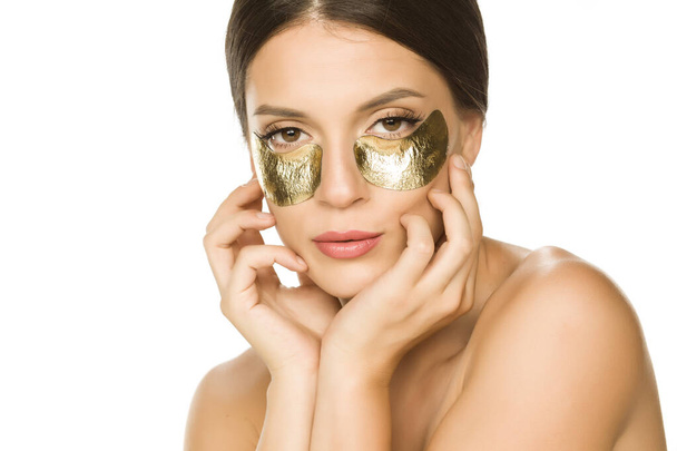 Young beautiful woman posing with golden patches under her eyes on white background - Photo, Image