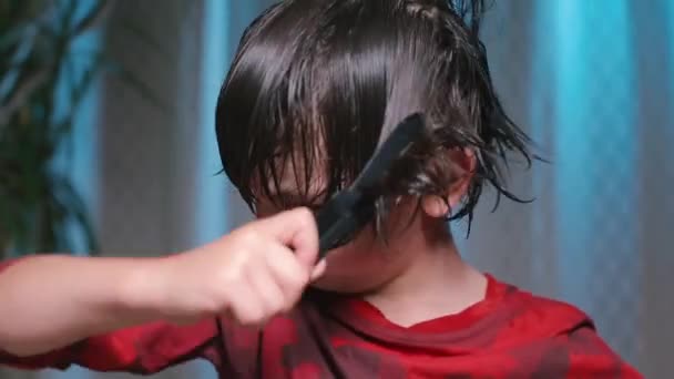 Close-up of a boys face. The boy is combing his hair. - Materiał filmowy, wideo