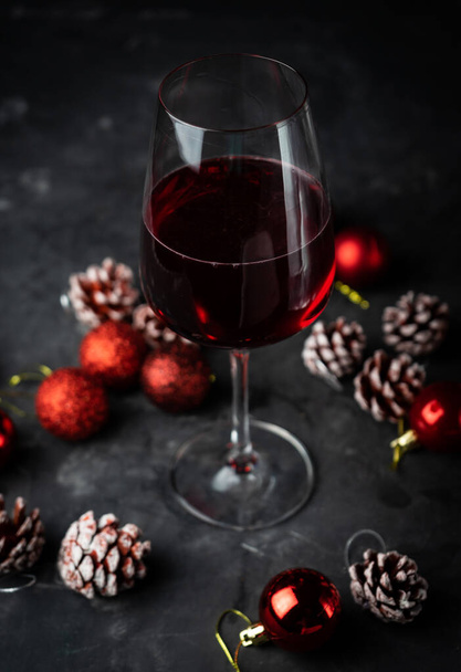una copa de vino tinto en decoraciones navideñas
 - Foto, Imagen