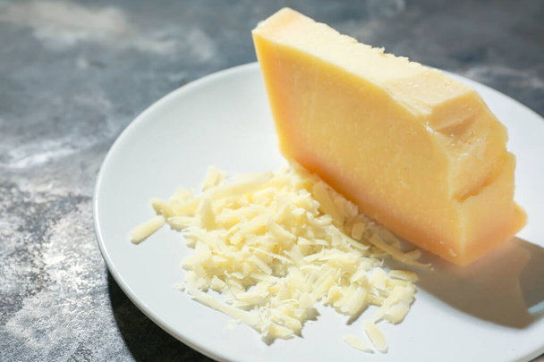 Placa con sabroso queso parmesano sobre fondo gris
 - Foto, Imagen