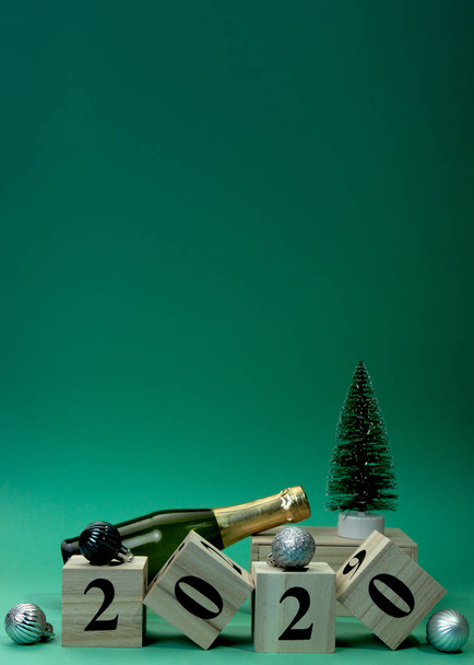 Σύνθεση Πρωτοχρονιάς με σαμπάνια μπουκαλιού και διακοσμητικό νέο έτος δέντρου. Ξύλινο κύβο μπλοκ οικοδόμηση της λέξης 2020. - Φωτογραφία, εικόνα