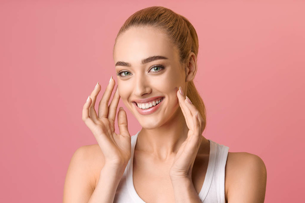 Woman with healthy skin touching her face and smiling - Foto, imagen