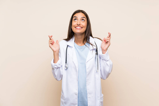 Young doctor woman over isolated background with fingers crossing - Фото, изображение
