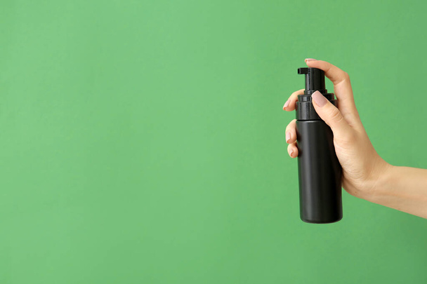 Female hand with cosmetic product in bottle on color background - Foto, afbeelding
