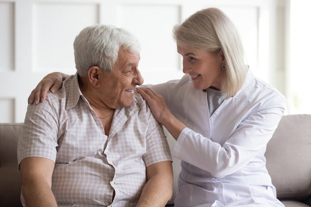 Mature female doctor showing care to elder male patient. - 写真・画像